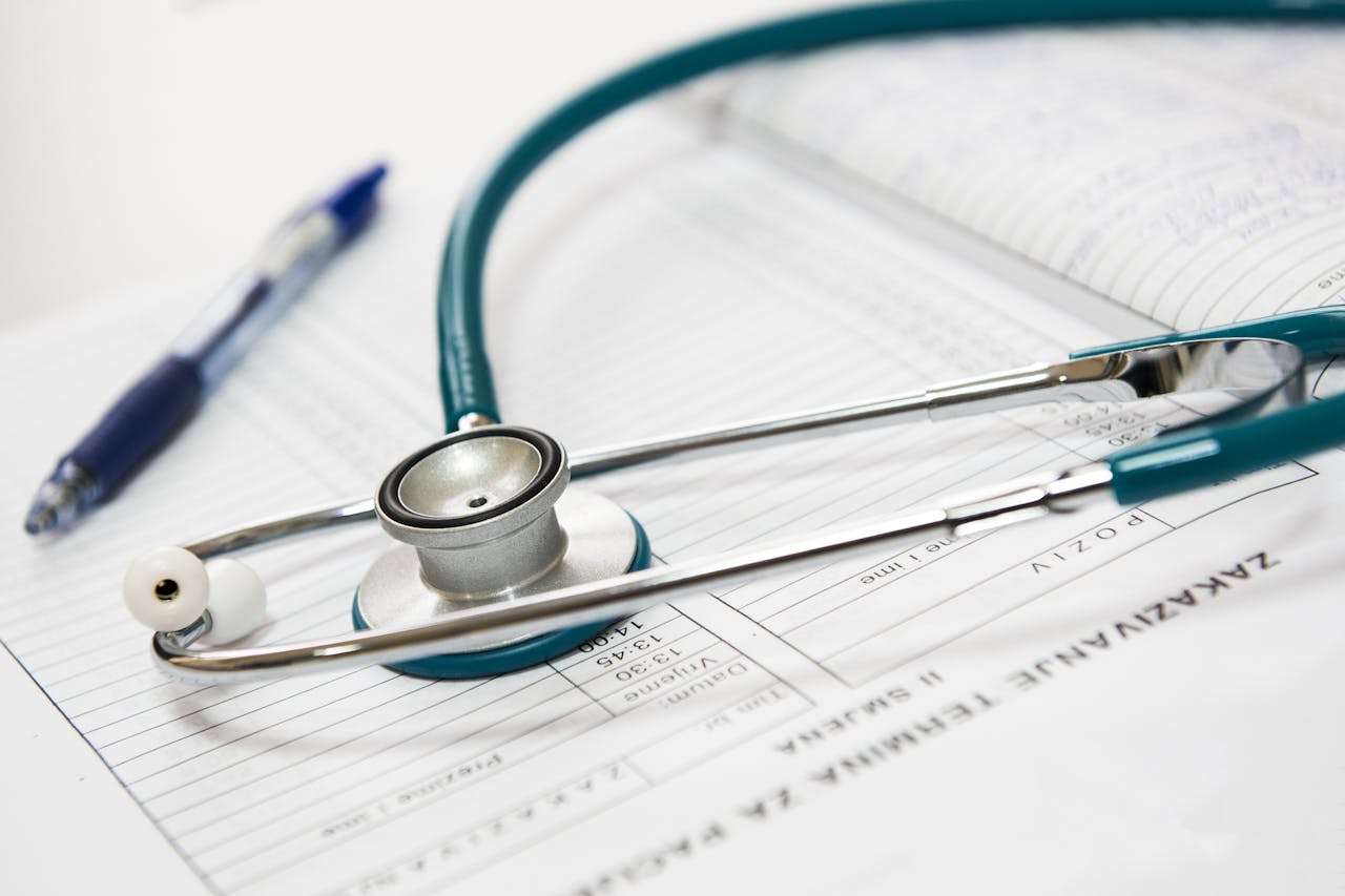 who-we-are A stethoscope and pen resting on a medical report in a healthcare setting.