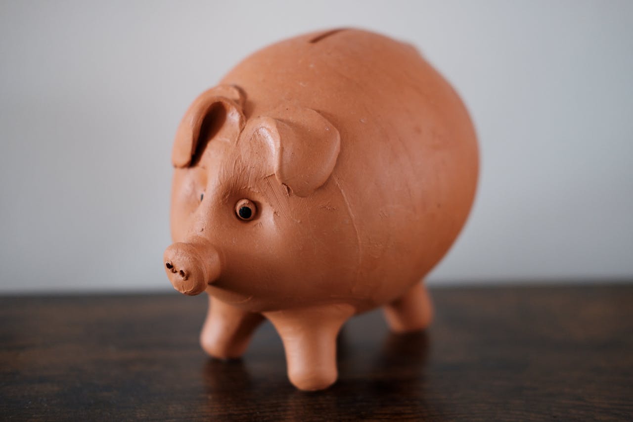 our-story Close-up of a terracotta piggy bank on a wooden table, symbolizing savings.