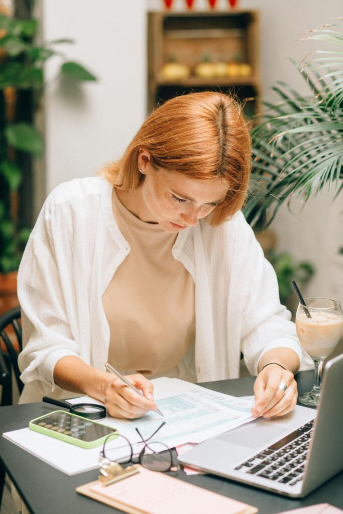 pexels photo 8927463 8927463 Woman analyzing financial documents using laptop and calculator indoors.